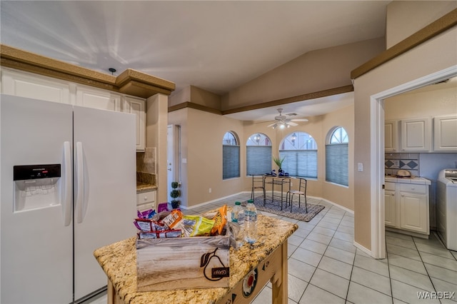 kitchen with backsplash, white refrigerator with ice dispenser, white cabinets, light tile patterned floors, and lofted ceiling