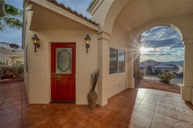 property entrance featuring a patio, a tile roof, and stucco siding