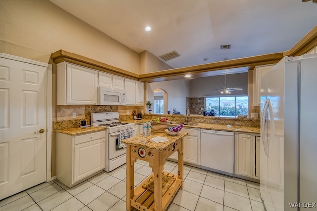 kitchen featuring white appliances, visible vents, arched walkways, a sink, and decorative backsplash