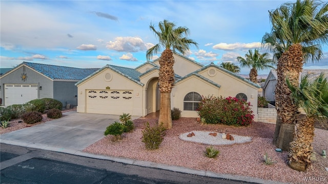 view of front of home with stucco siding, driveway, a tile roof, and a garage