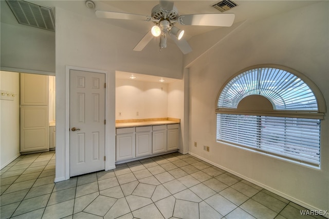 empty room with light tile patterned floors, visible vents, a wealth of natural light, and ceiling fan