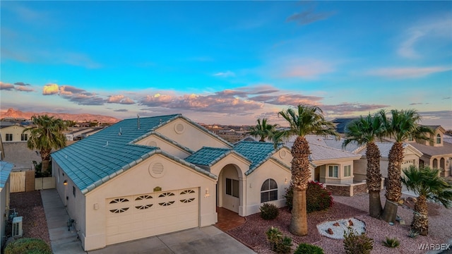 view of front of property with a tiled roof, a garage, driveway, and stucco siding