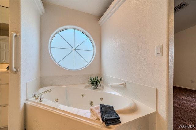 full bath with vanity, a textured wall, visible vents, and a whirlpool tub