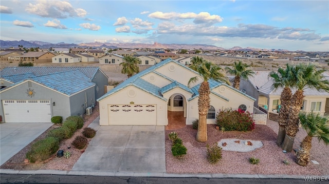 view of front of house featuring stucco siding, driveway, a mountain view, a residential view, and an attached garage