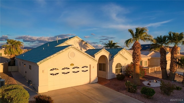 view of front of home featuring stucco siding, a garage, concrete driveway, and a tile roof