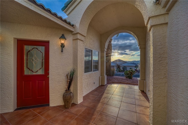 entrance to property with a tile roof and stucco siding