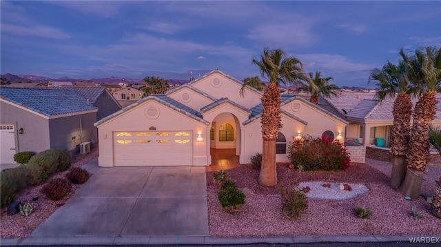 mediterranean / spanish home with cooling unit, an attached garage, stucco siding, concrete driveway, and a tile roof