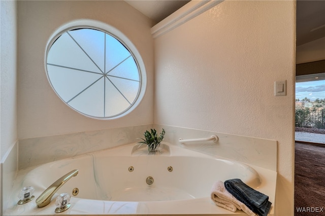 bathroom featuring a whirlpool tub and a textured wall