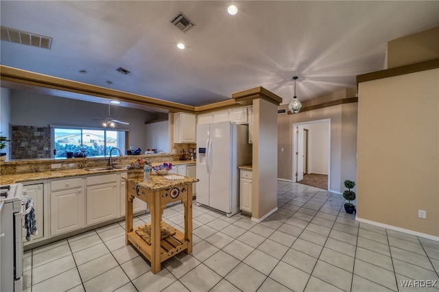 kitchen with visible vents, stainless steel range with electric stovetop, a sink, white fridge with ice dispenser, and white cabinets