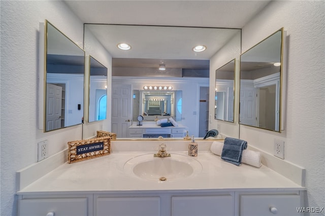 bathroom featuring recessed lighting, vanity, and a textured wall