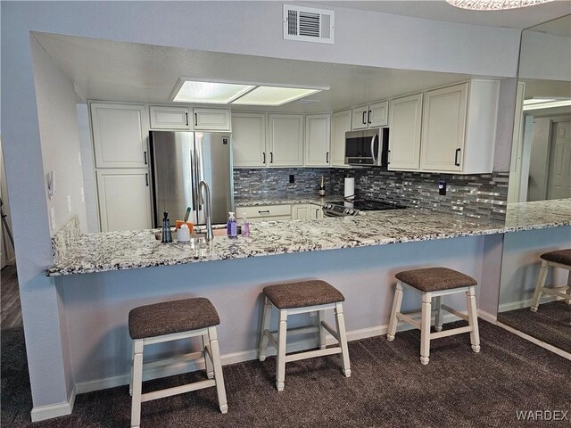 1800 Clubhouse Dr Unit 89, Bullhead City, AZ 86442 - kitchen with a peninsula, backsplash, light stone countertops, visible vents, and appliances with stainless steel finishes