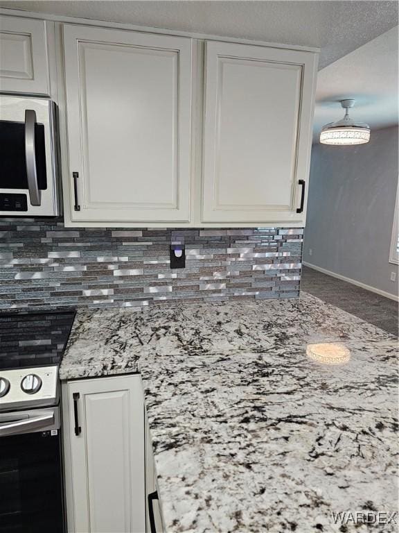 1800 Clubhouse Dr Unit 89, Bullhead City, AZ 86442 - kitchen featuring stainless steel microwave, white cabinets, light stone countertops, range with electric cooktop, and decorative backsplash