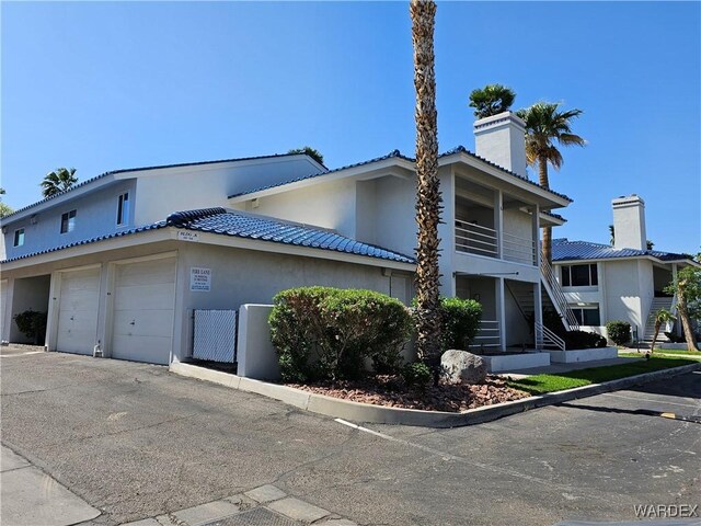 1800 Clubhouse Dr Unit 89, Bullhead City, AZ 86442 - view of property with stucco siding, a chimney, stairway, driveway, and an attached garage
