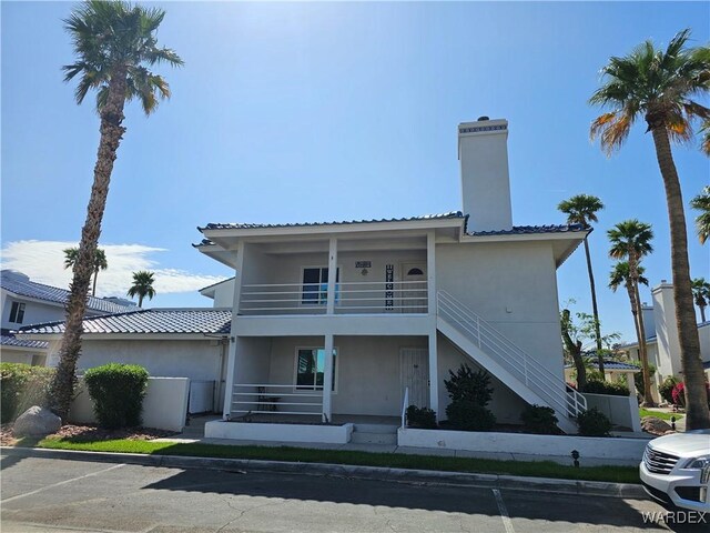 1800 Clubhouse Dr Unit 89, Bullhead City, AZ 86442 - exterior space with covered porch, stucco siding, stairs, a chimney, and a balcony