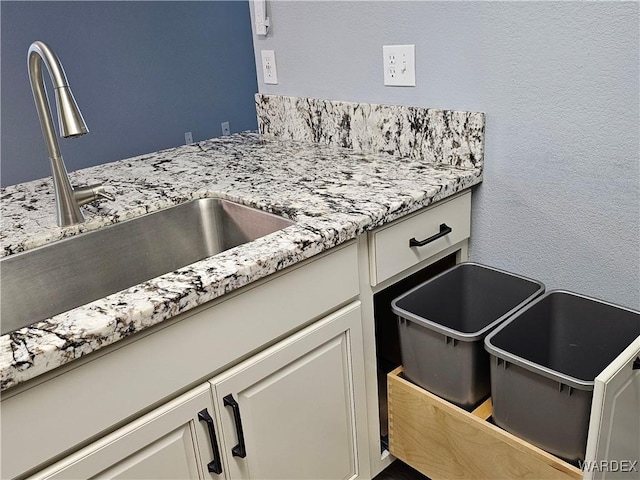 1800 Clubhouse Dr Unit 89, Bullhead City, AZ 86442 - interior details featuring light stone counters, a textured wall, a sink, and white cabinetry