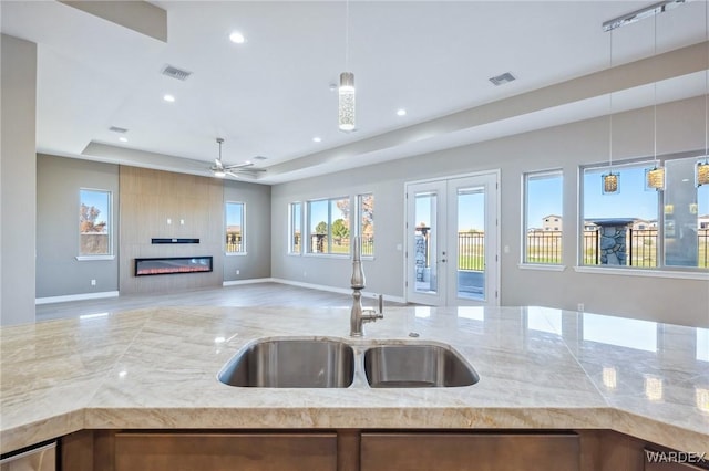 kitchen with a fireplace, visible vents, open floor plan, a raised ceiling, and decorative light fixtures