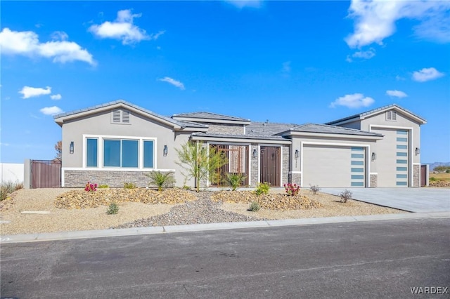 view of front of home with a garage, fence, stone siding, driveway, and stucco siding