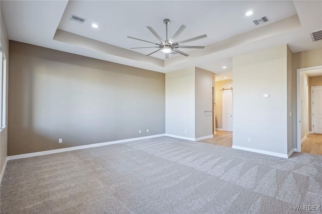 unfurnished bedroom featuring baseboards, visible vents, and a tray ceiling