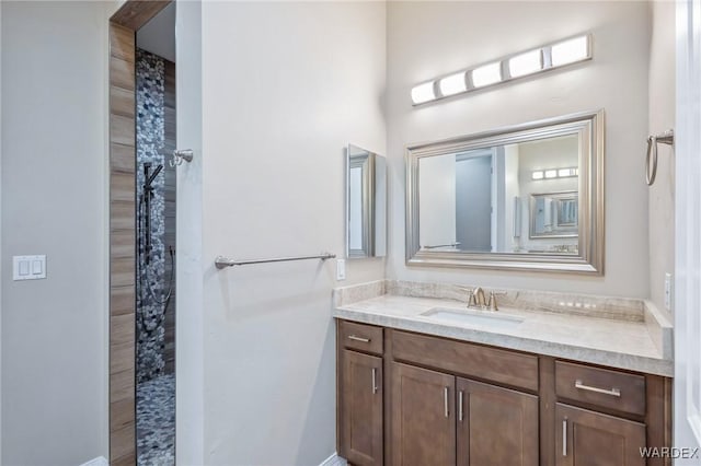 bathroom featuring tiled shower and vanity