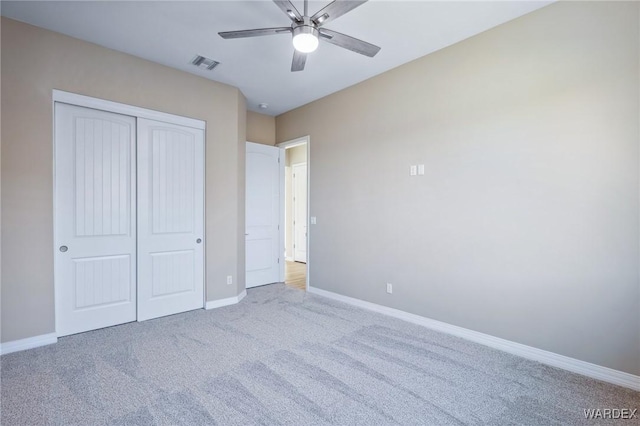 unfurnished bedroom with a closet, visible vents, light carpet, and baseboards