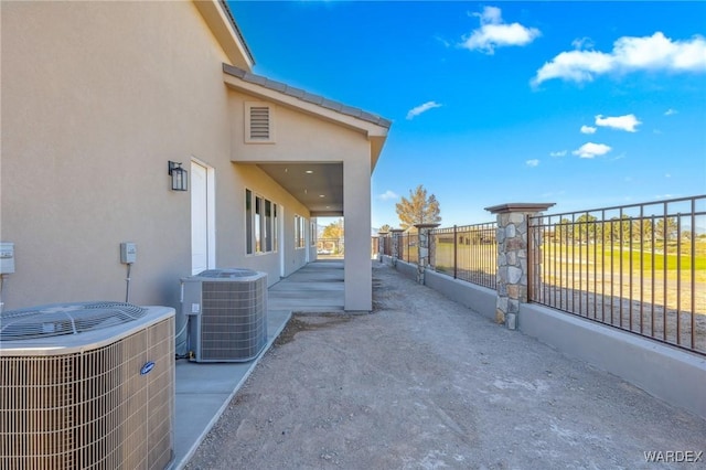 view of home's exterior featuring fence, cooling unit, and stucco siding