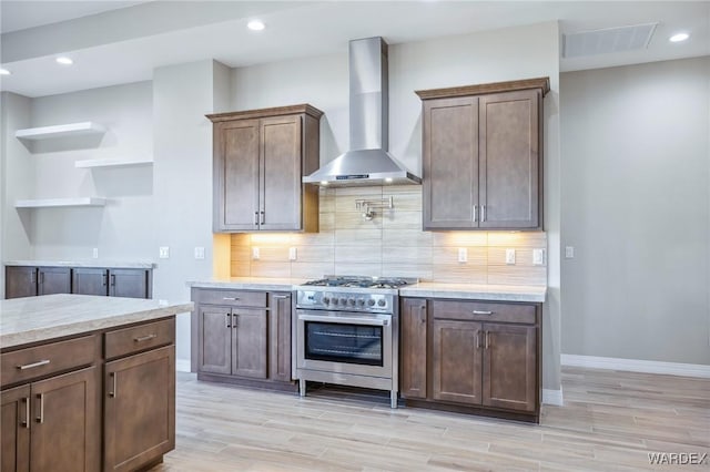 kitchen with visible vents, wall chimney range hood, decorative backsplash, and high end stainless steel range