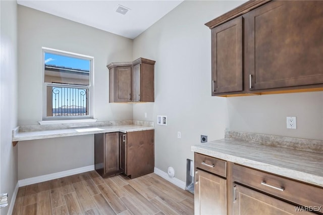 kitchen with dark brown cabinetry, wood tiled floor, visible vents, and baseboards