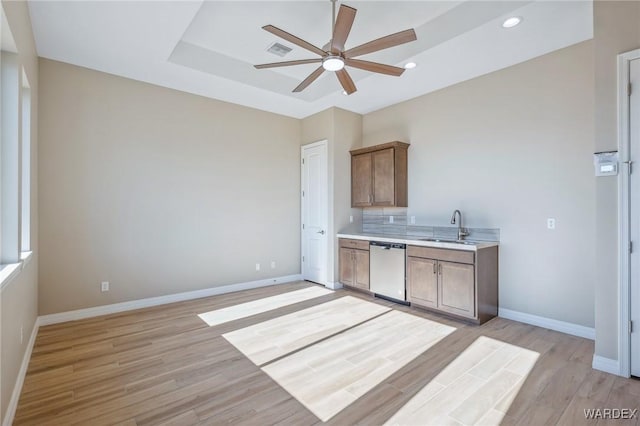 kitchen with visible vents, a tray ceiling, light countertops, stainless steel dishwasher, and a sink