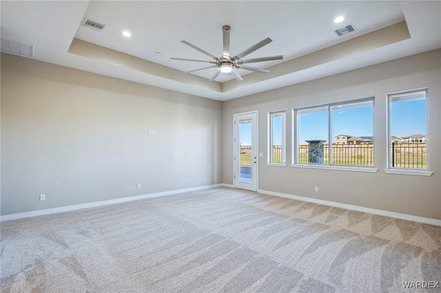 spare room with baseboards, visible vents, and a raised ceiling