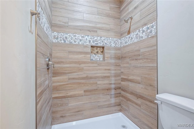 bathroom with toilet and a tile shower