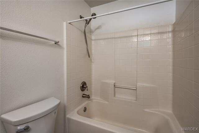 full bath featuring toilet, tub / shower combination, and a textured wall