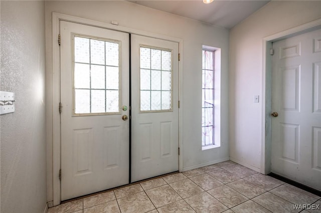 doorway with light tile patterned floors and baseboards