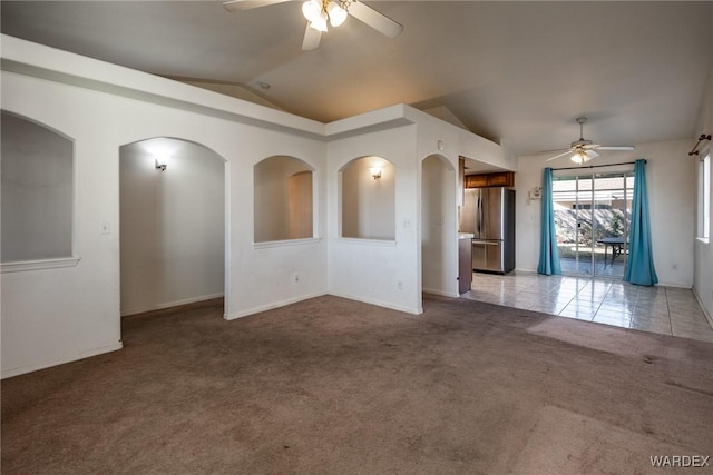 unfurnished room featuring lofted ceiling, light tile patterned floors, a ceiling fan, and light colored carpet