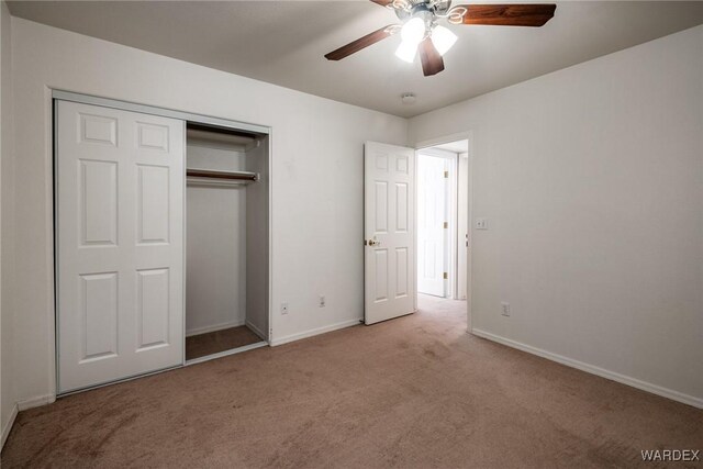 unfurnished bedroom featuring baseboards, ceiling fan, a closet, and light colored carpet