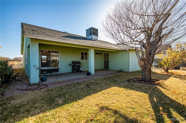 rear view of property with stucco siding, cooling unit, a lawn, and a patio