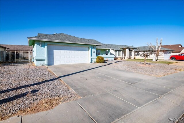 view of front facade featuring driveway, a residential view, an attached garage, fence, and stucco siding