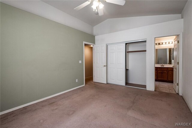 unfurnished bedroom with light carpet, a closet, lofted ceiling, ensuite bath, and a sink