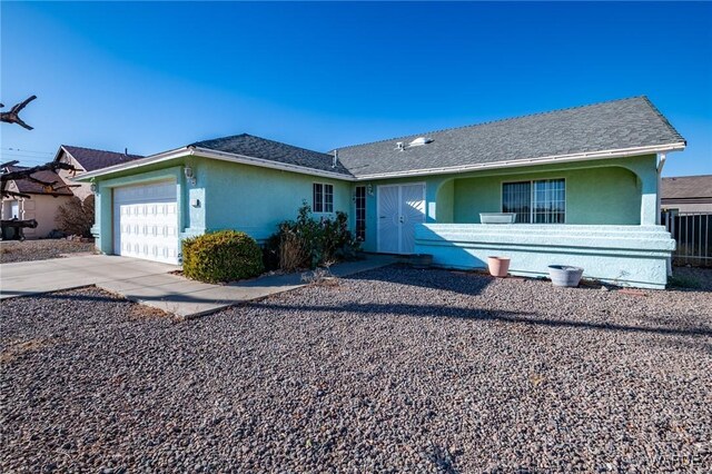 ranch-style house with driveway, roof with shingles, an attached garage, and stucco siding