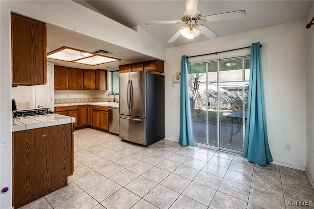 kitchen with light tile patterned floors, visible vents, brown cabinetry, appliances with stainless steel finishes, and a sink