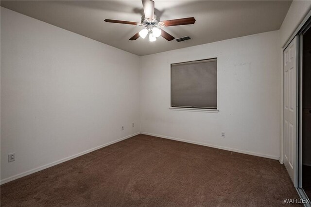 unfurnished bedroom with ceiling fan, visible vents, baseboards, a closet, and dark carpet