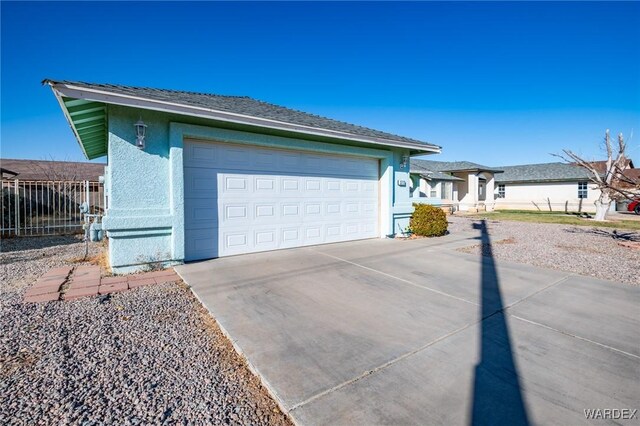 view of property exterior featuring an outbuilding, stucco siding, fence, a garage, and driveway