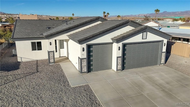 single story home with a tile roof, stucco siding, an attached garage, a mountain view, and driveway