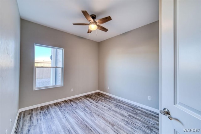 unfurnished room with light wood finished floors, a ceiling fan, and baseboards