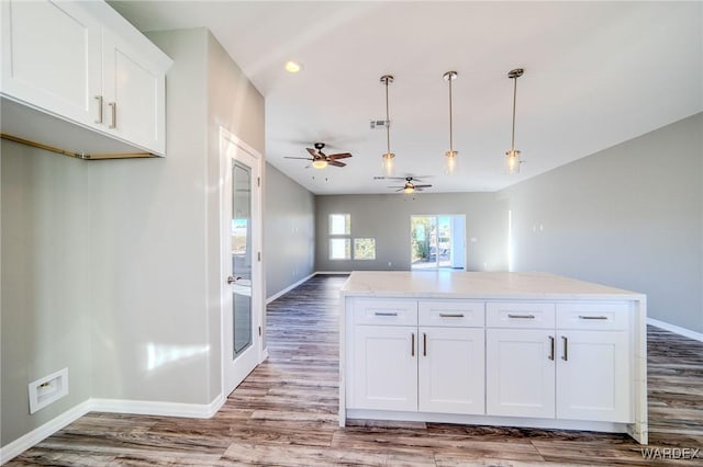 kitchen featuring hanging light fixtures, light stone counters, white cabinets, and open floor plan