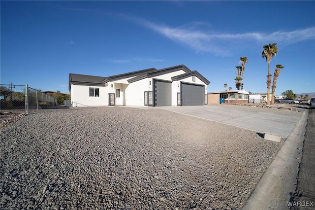 view of front of home with a garage, concrete driveway, fence, and stucco siding