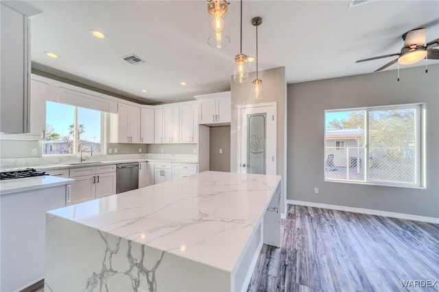 kitchen featuring light stone counters, visible vents, hanging light fixtures, white cabinetry, and a kitchen island