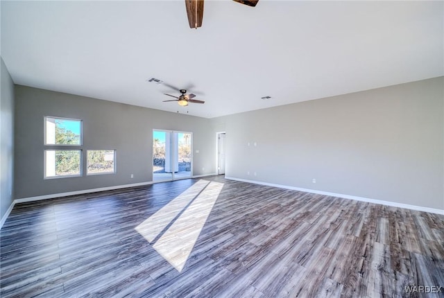 spare room with dark wood-style flooring, visible vents, and baseboards