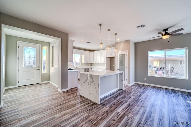 kitchen featuring a healthy amount of sunlight, white cabinets, decorative light fixtures, and a center island