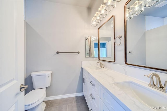 bathroom featuring baseboards, a sink, toilet, and tile patterned floors