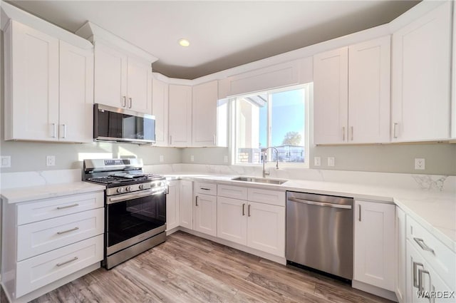 kitchen with recessed lighting, appliances with stainless steel finishes, light wood-style floors, white cabinetry, and a sink